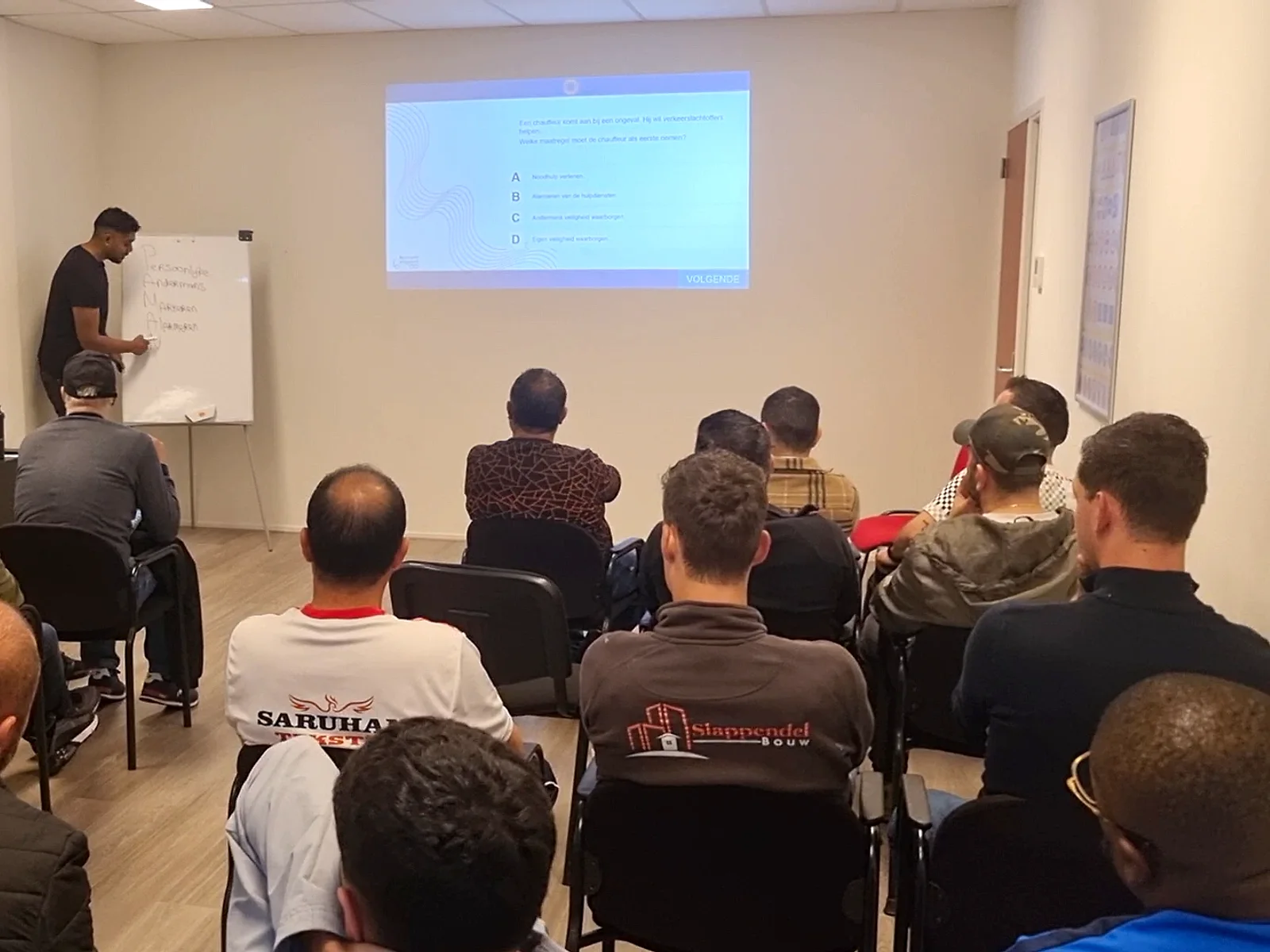 Instructeur geeft klassikale uitleg aan een volle groep cursisten