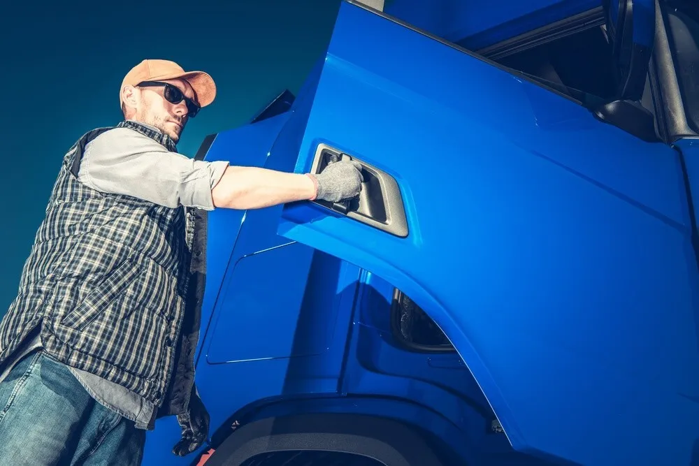 Nuvrachtwagen – Vrachtwagenchauffeur die een blauwe vrachtwagen deur open doet – Theorie
